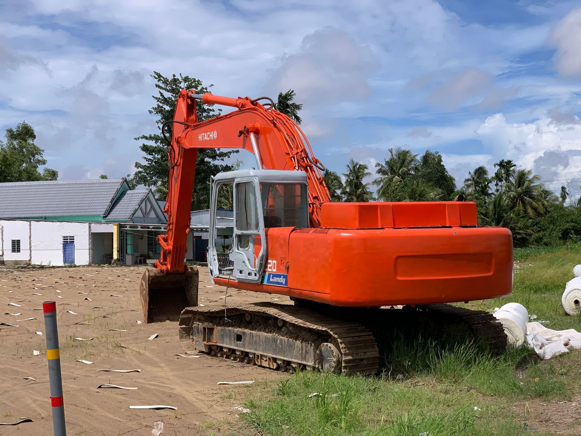 Orange excavator on tracks at a construction site under a cloudy sky