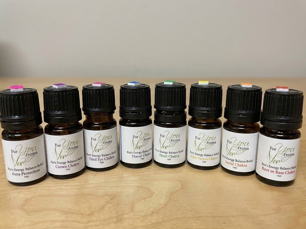 Seven small amber essential oil bottles with black caps lined up on a wooden table against a plain wall.
