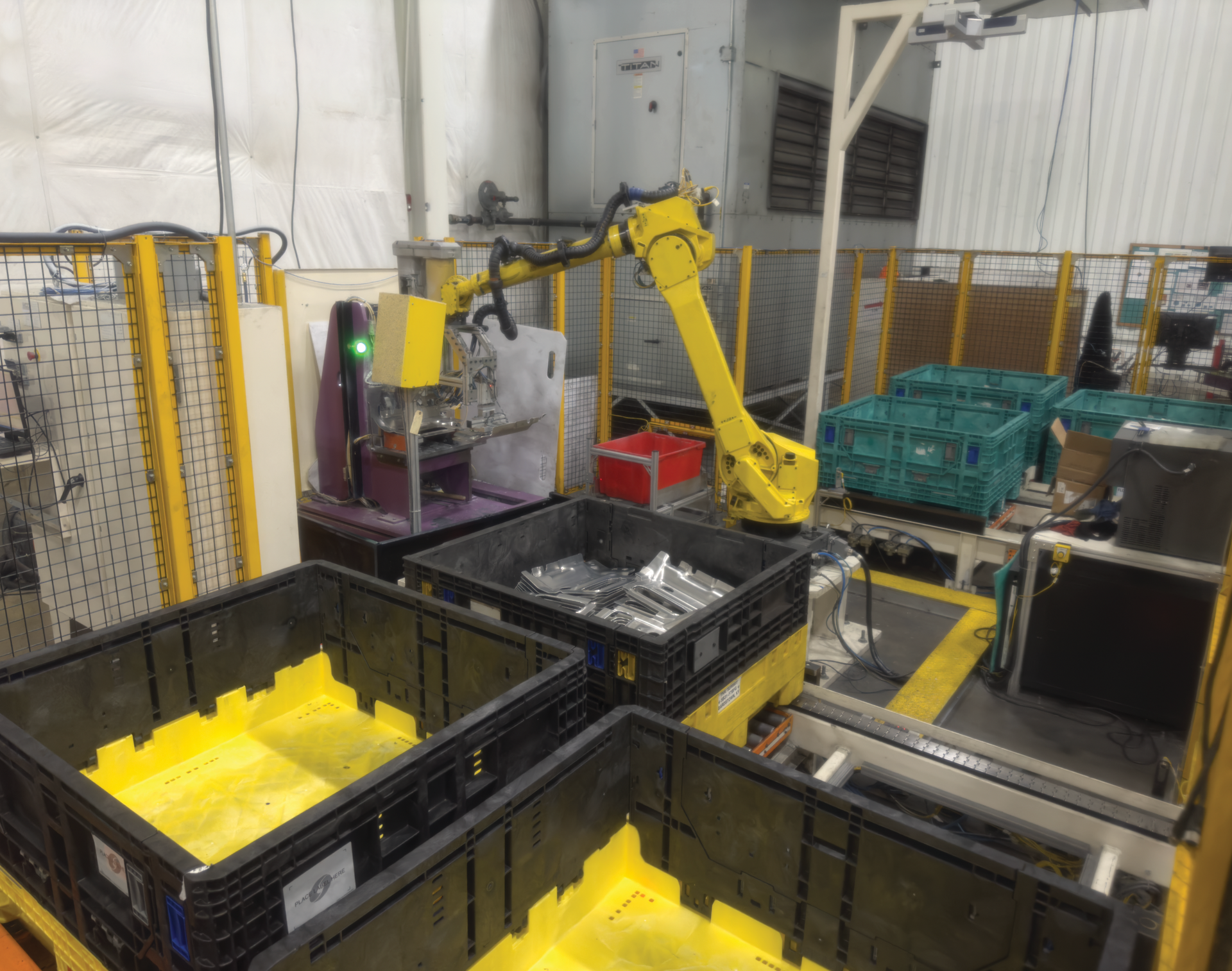 A robotic arm is moving crates in a factory.
