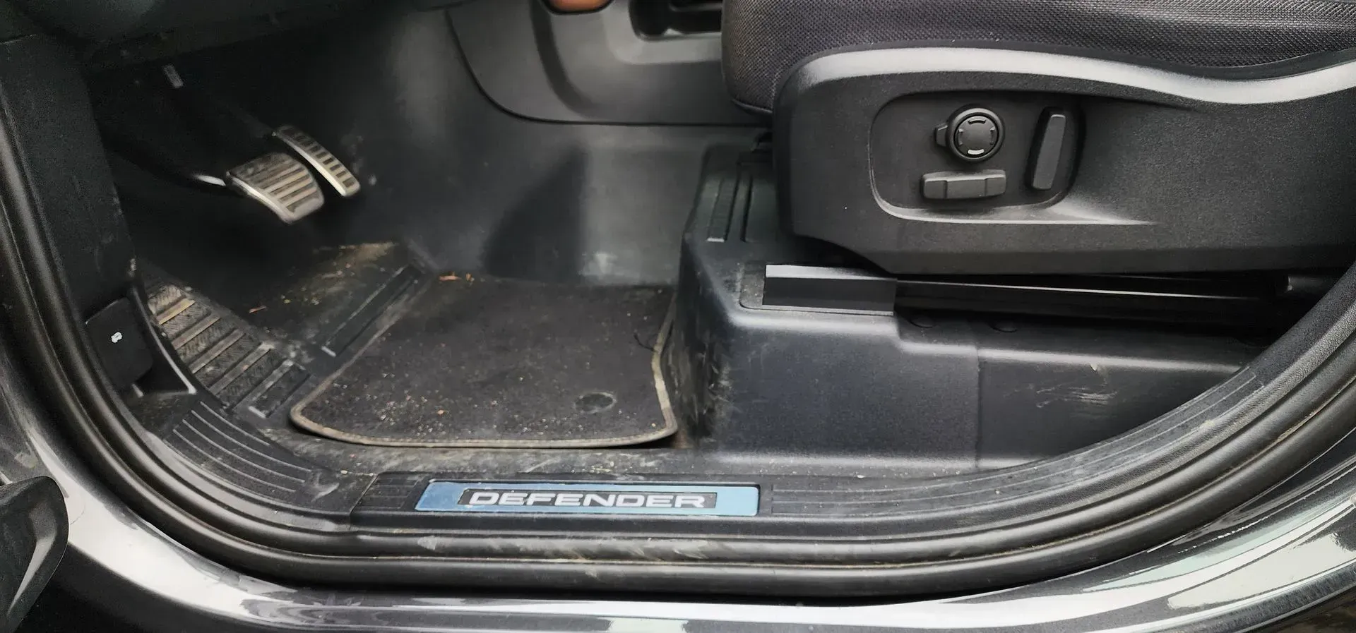 Car door sill and floor mat with a blue Mercedes-Benz trim plate, showing the lower interior step area.