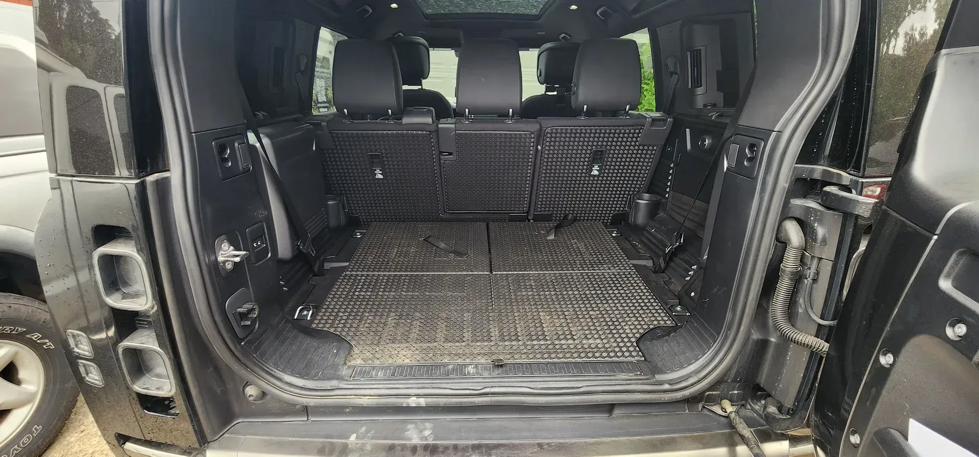 Open black SUV cargo area with rear seats folded flat and a rubber cargo mat