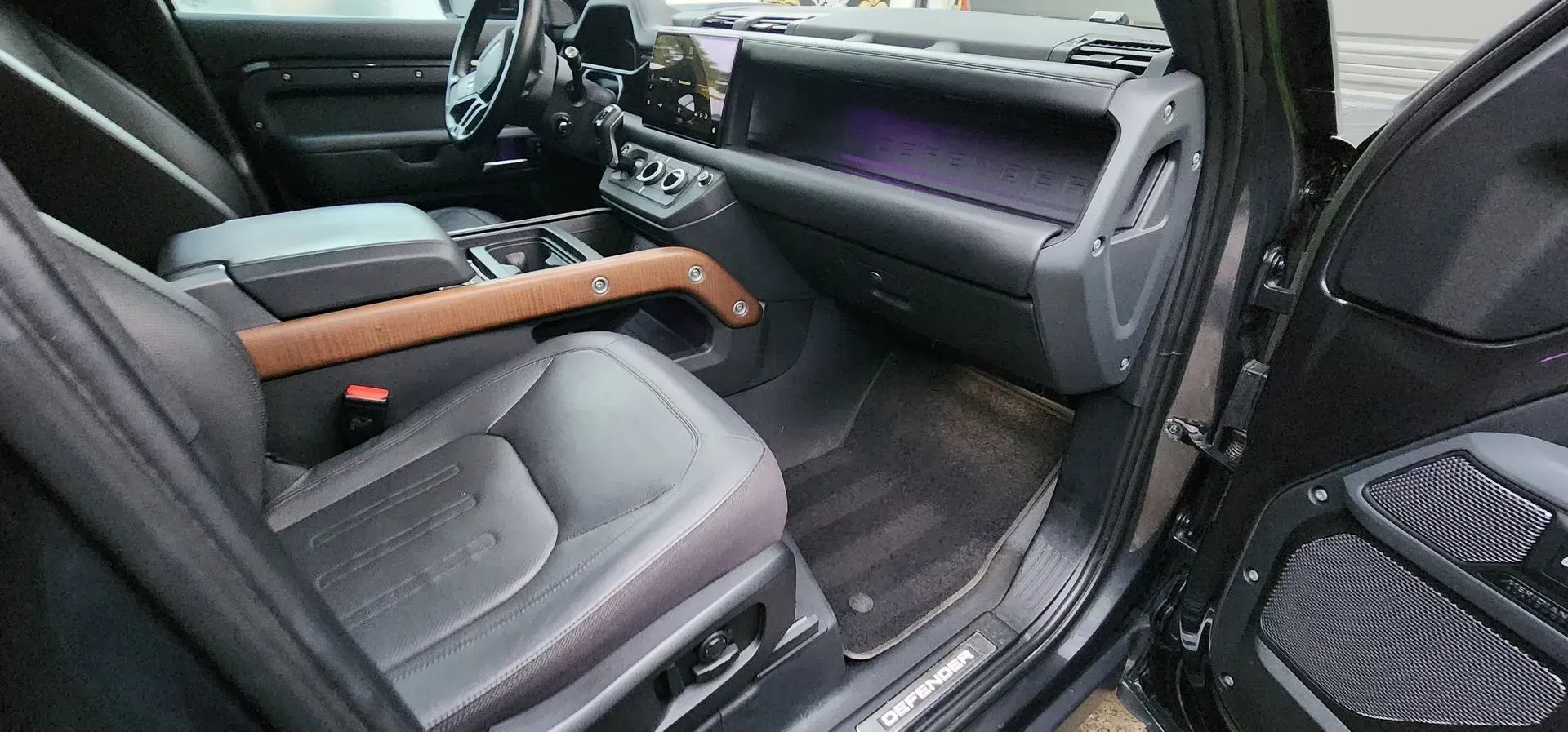 Car interior with gray seats, black dashboard, and a wooden handrail across the front seats.