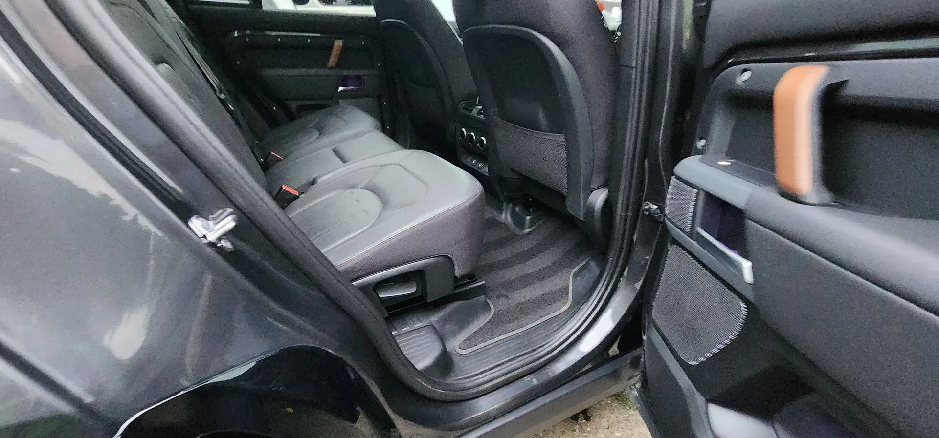 Car interior with rear seat door open, showing black upholstery and a gray seat
