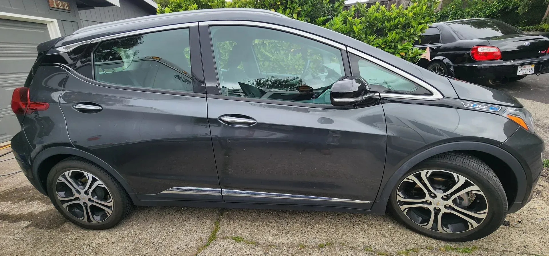 Dark gray compact SUV parked on a wet street, side view with alloy wheels.