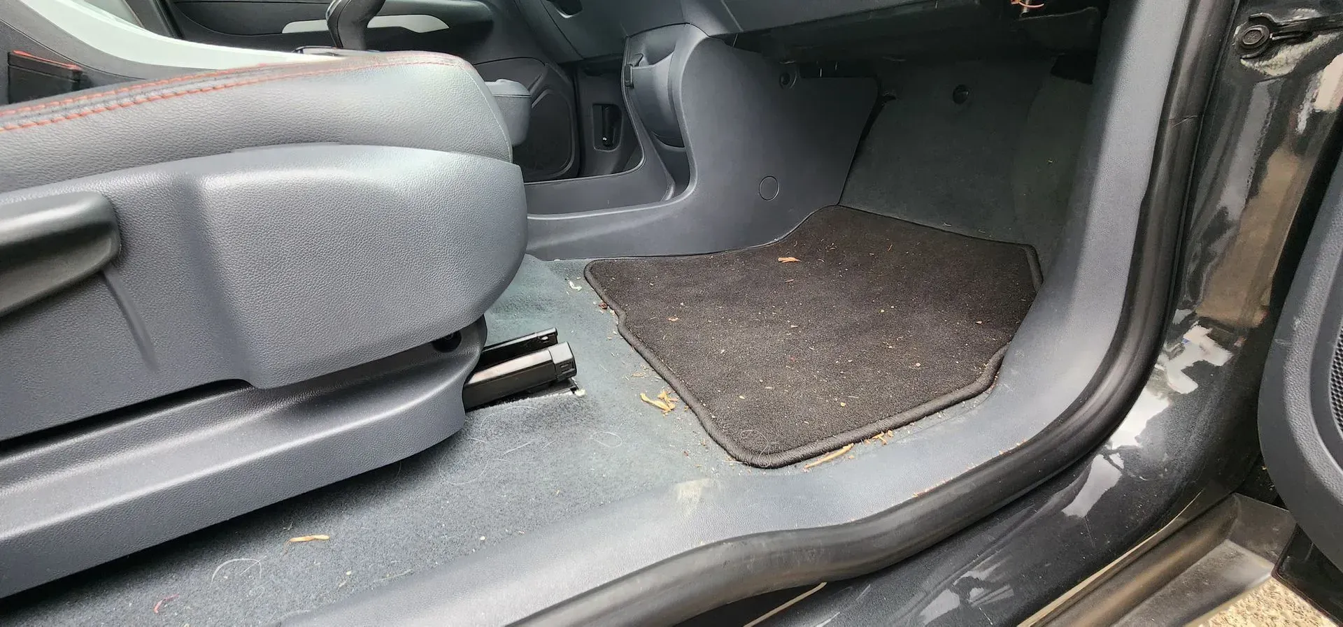 Car interior with rear seat folded down and a floor mat visible near the door.