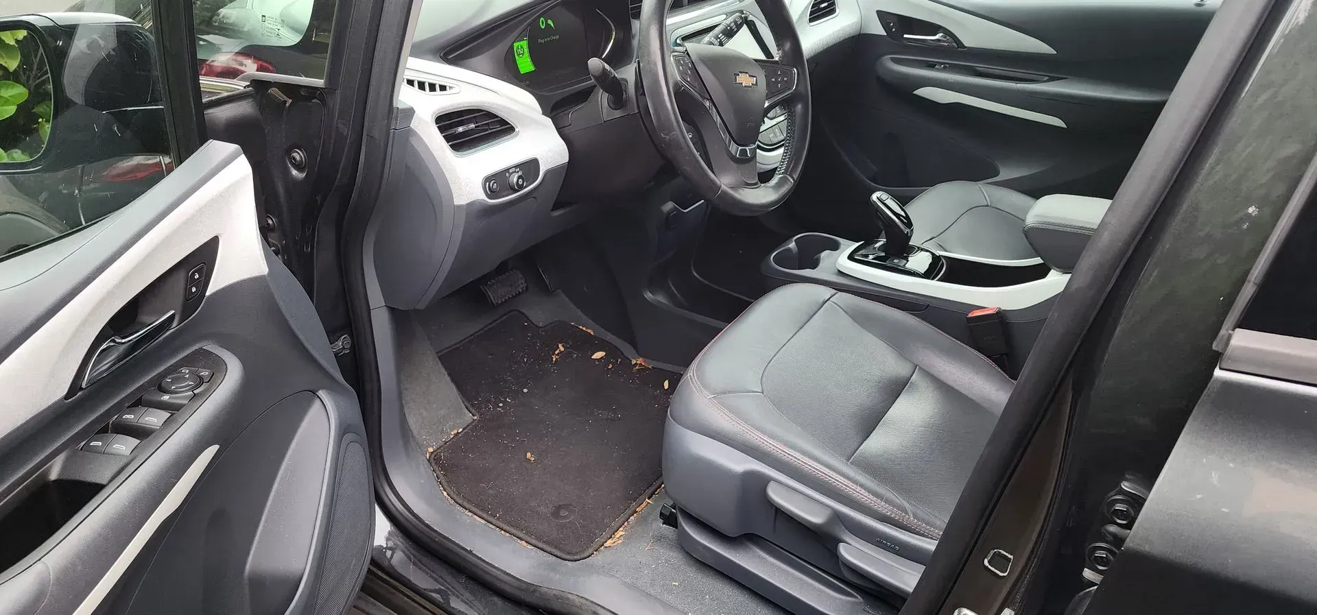 Open car door showing black interior with dashboard, steering wheel, and front seat.