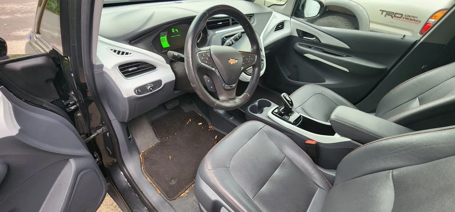Car interior with steering wheel, front seats, and open door, showing dashboard and center console