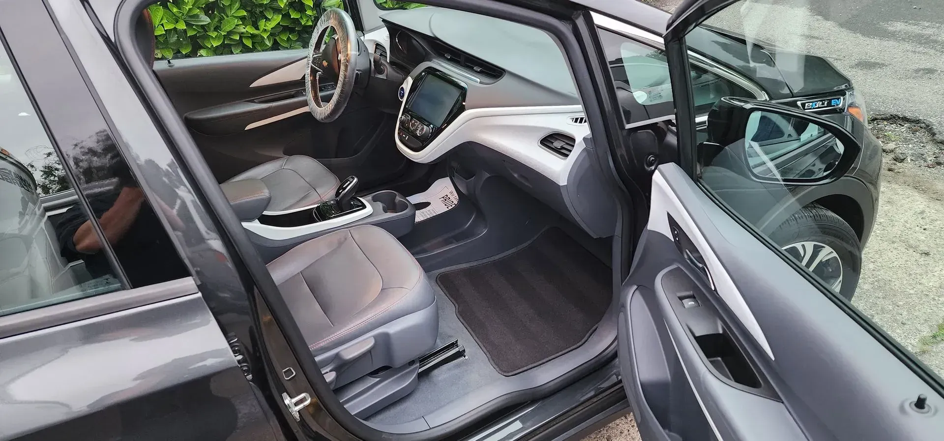 Open car door showing a gray interior with seats and dashboard in a driveway