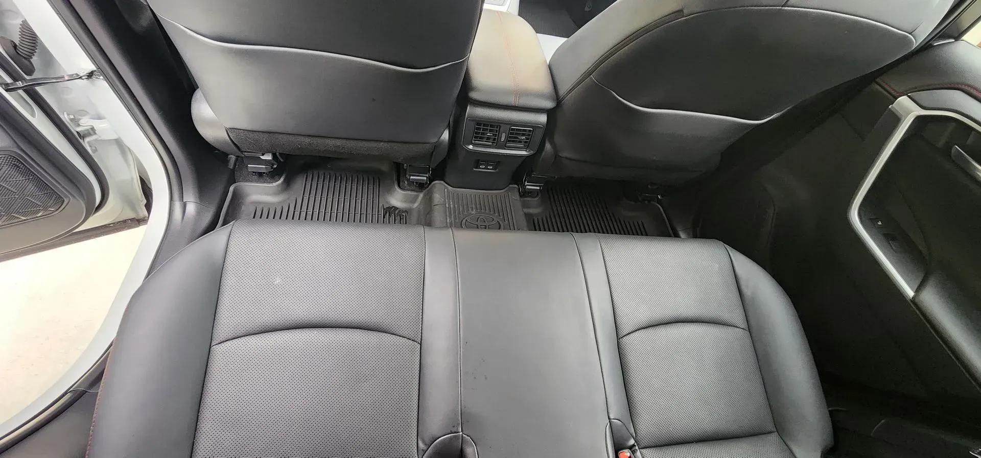 Rear car seat with black upholstery and a central armrest folded down