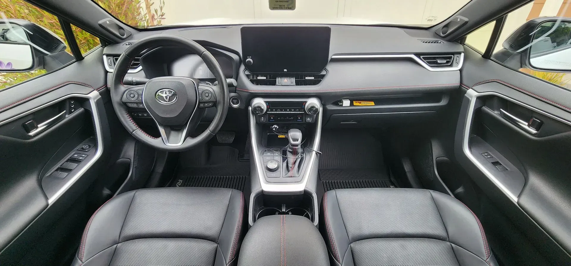 Car interior view of a modern Toyota dashboard, steering wheel, center console, and front seats