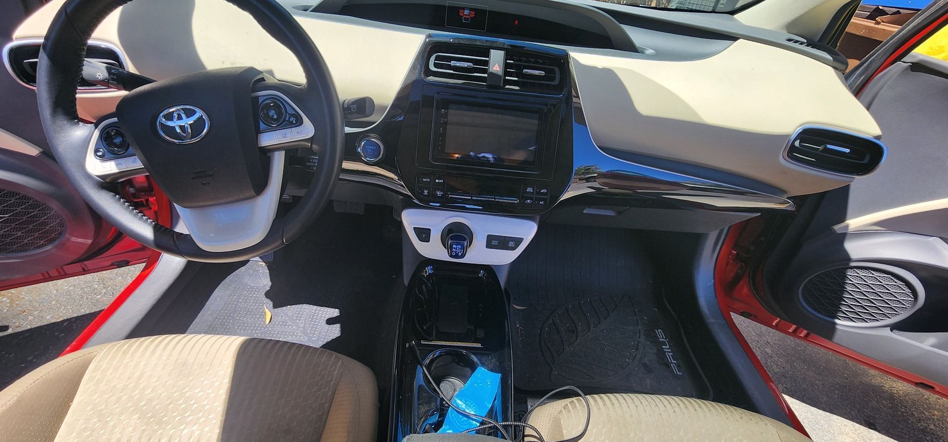 Car interior with steering wheel, dashboard display, center console, and beige seats.