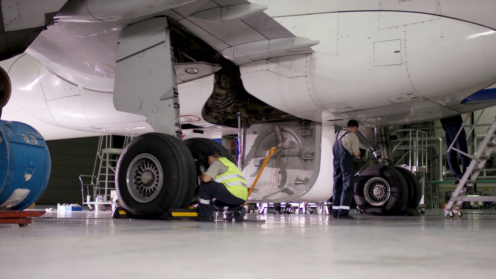 Airplane undercarriage in hangar with mechanics inspecting landing gear and engine