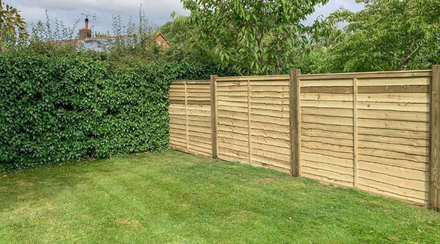 Sturdy horizontal wood panel privacy fence in a residential backyard.