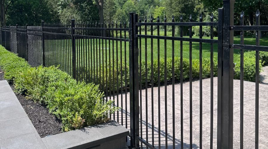 Black ornamental metal fencing bordering a manicured yard and patio.