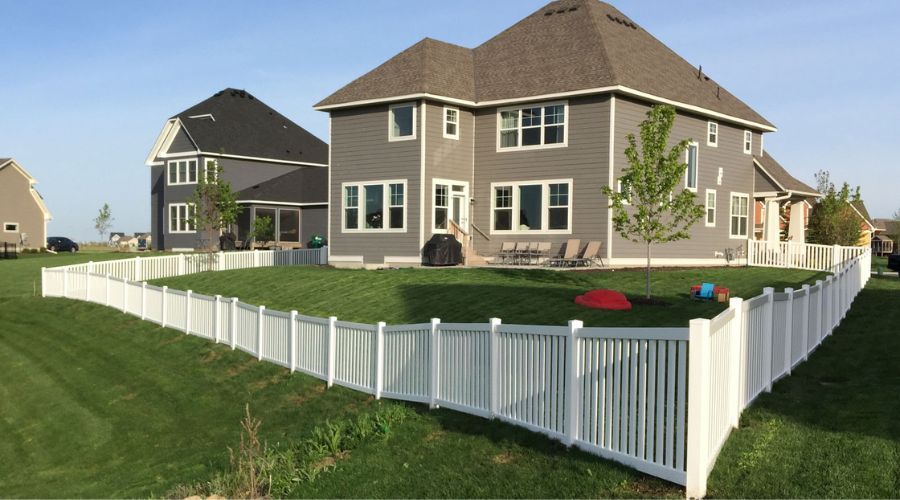 Suburban house with white picket fence and manicured lawn on a sunny day