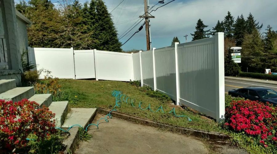 White vinyl fence in a residential yard, highlighting easy maintenance requirements.