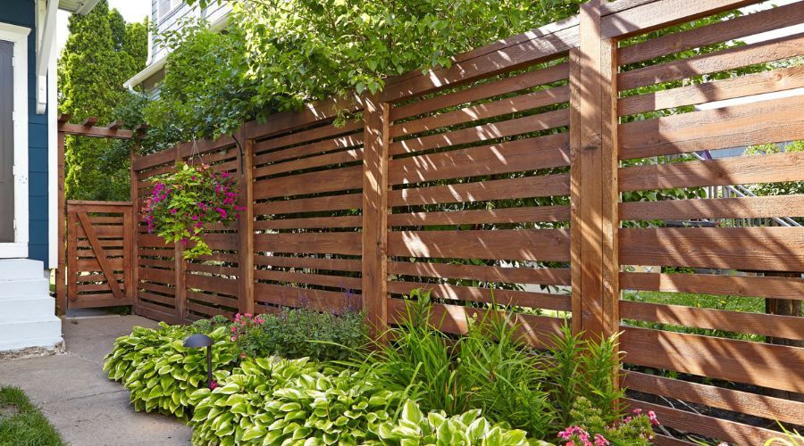 Modern horizontal wood privacy fence beside a landscaped home