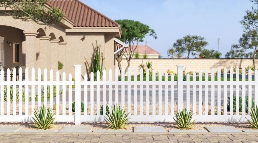Classic white vinyl picket fence installed in front of a modern home with desert landscaping