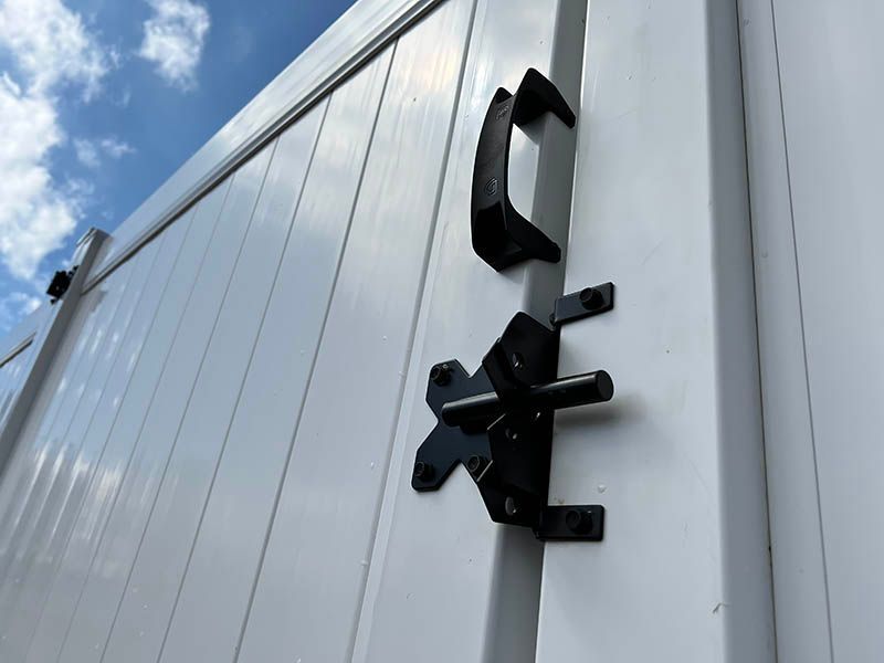 Black metal letters mounted on a white corrugated building against a blue sky
