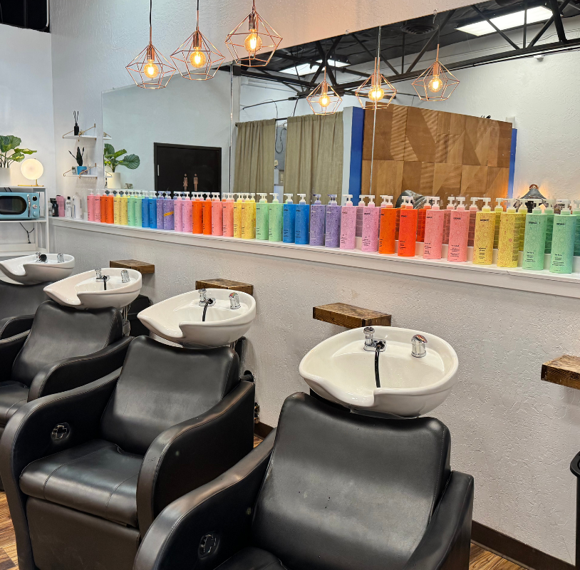Hair salon interior with wash stations, black chairs, and colorful product display.
