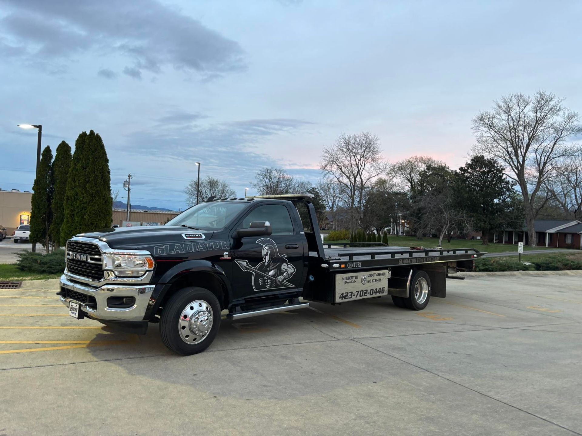 Black pickup truck with heavy front-end damage parked on a road at dusk