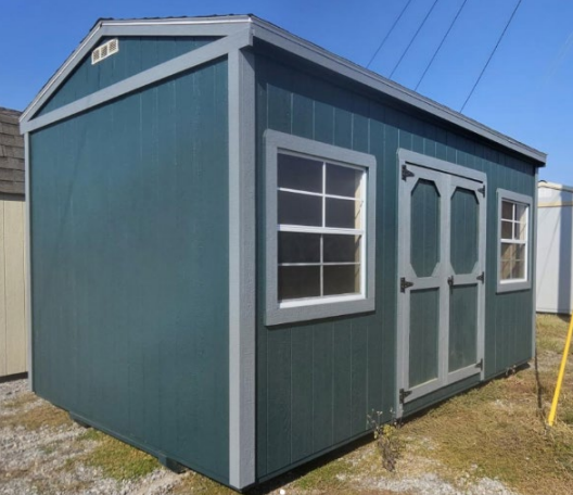 Blue shed with gray trim, two windows, and double doors on a grassy lot.