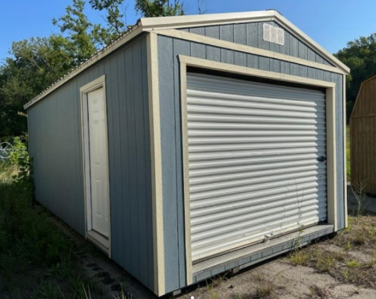 Blue shed with a garage door and side door, beige trim, outdoors.