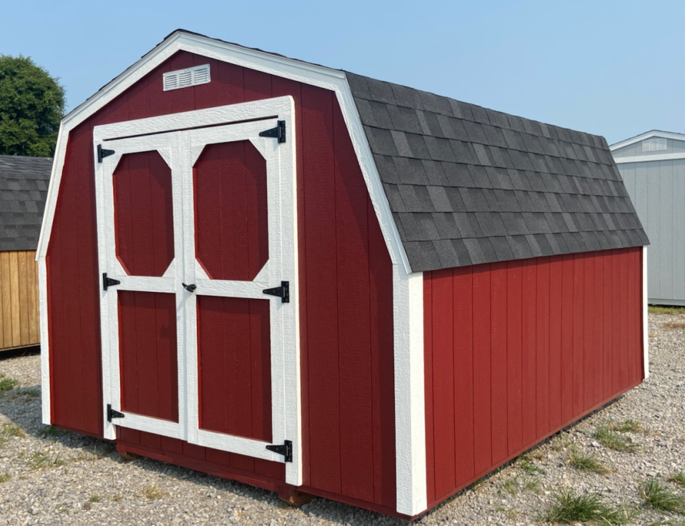 Red barn shed with white trim, double doors, and gray shingle roof.