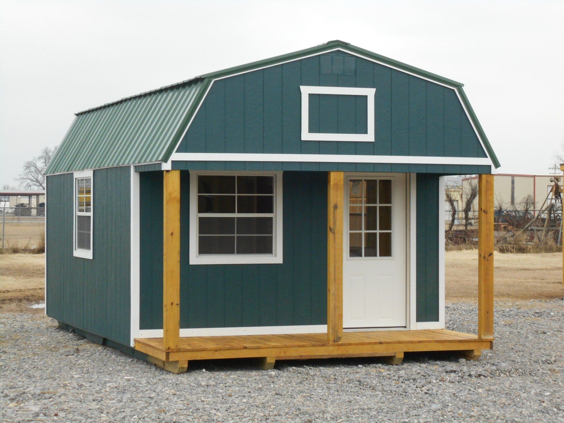 Green shed with a porch and white trim.