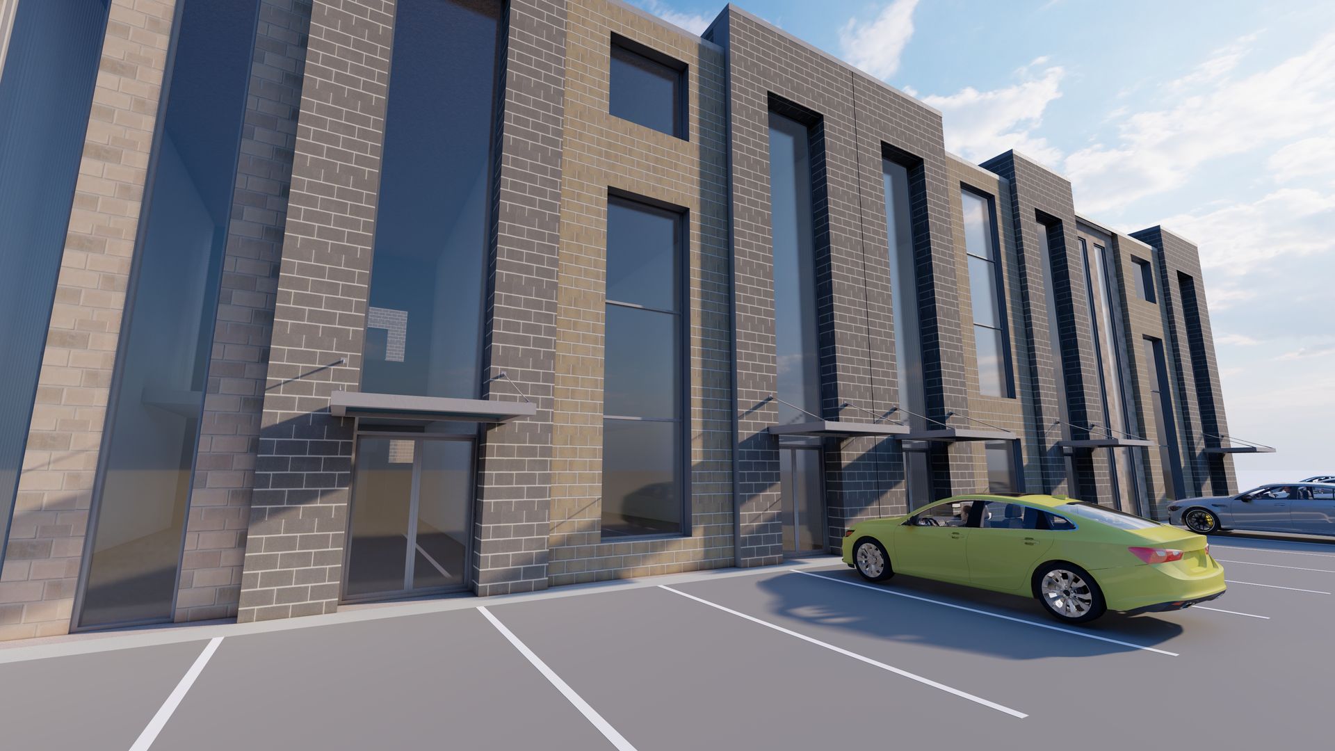 A modern, multi-unit gray brick building with tall windows and small metal canopies over glass entry doors in a parking lot.