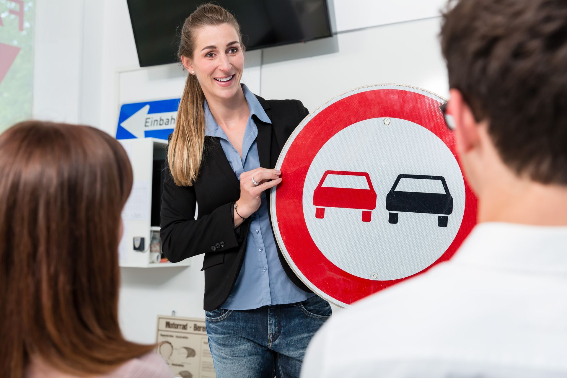 Driving instructor explaining meaning of street sign to class of students.