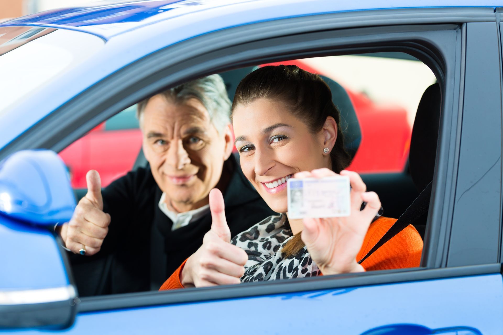 Driving School - Young woman steer a car, maybe she has a driving test, she holding proudly her driving license then she has passed.