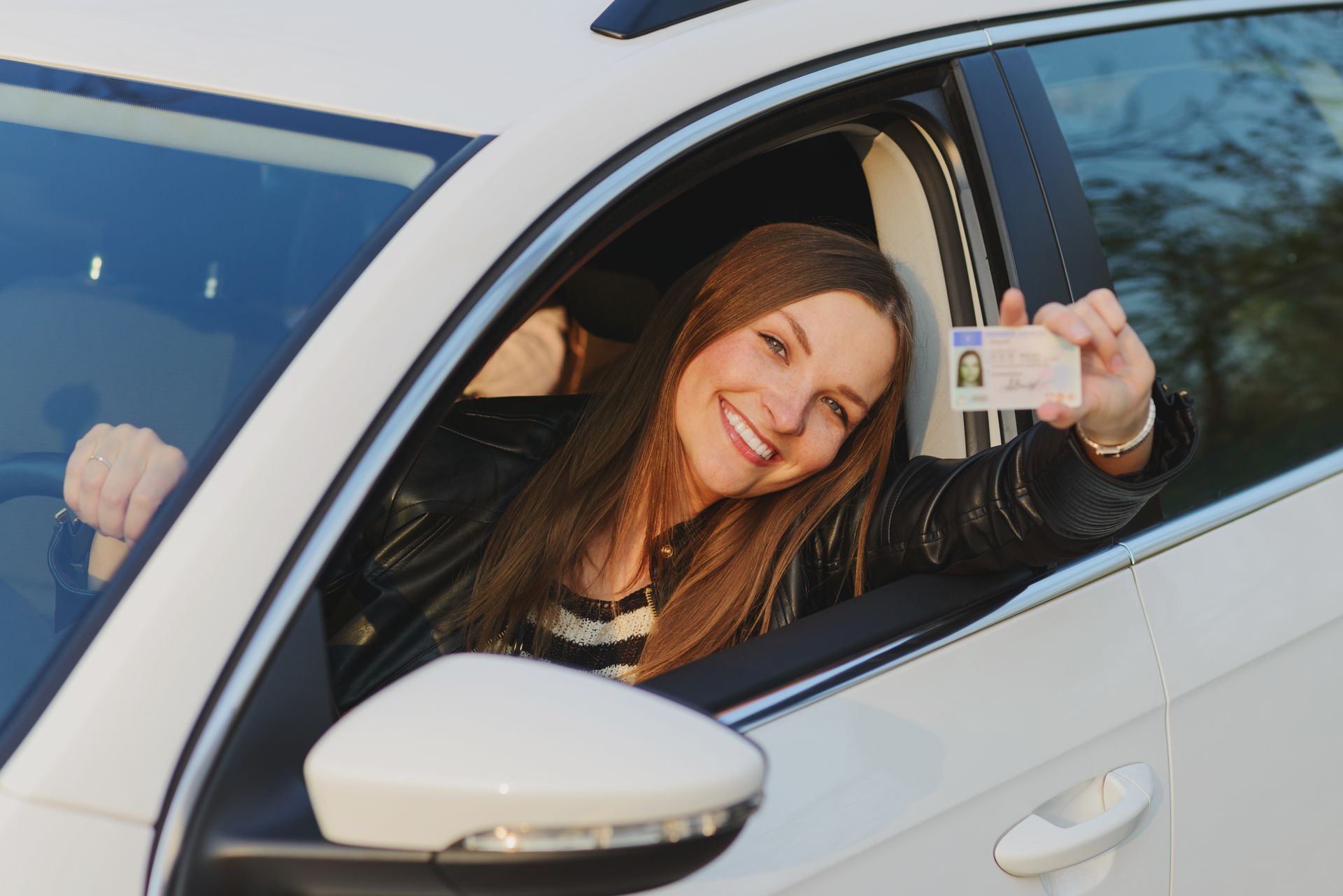 Attractive young brunette woman proudly showing her drivers license.