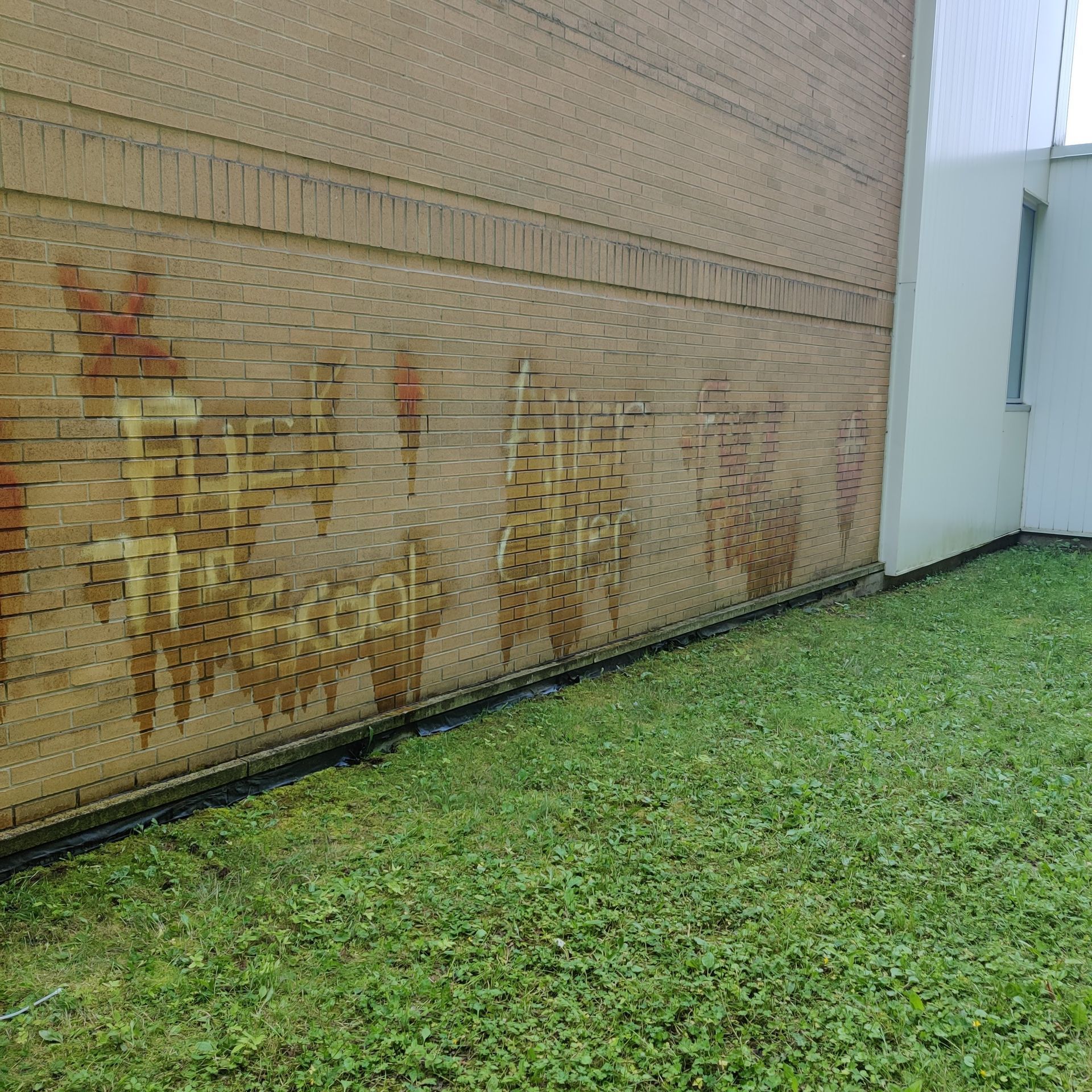 Un mur de briques avec des graffitis dessus qui disent l'école