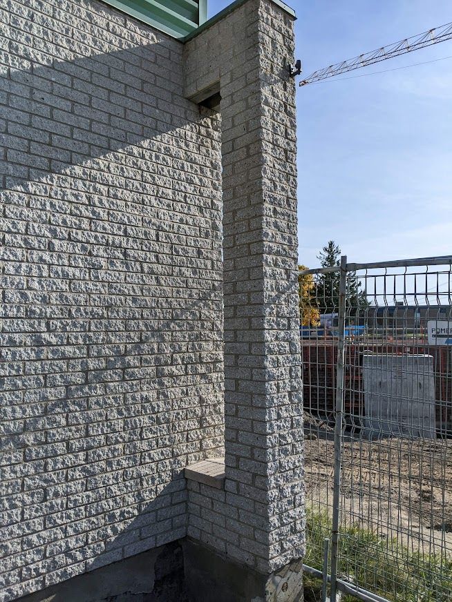 Un mur de briques blanches avec une clôture en arrière-plan