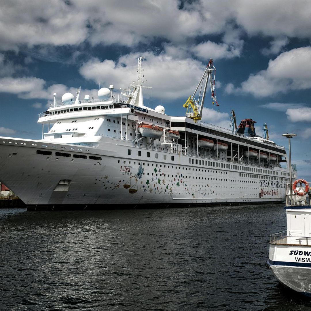 Ein großes Kreuzfahrtschiff liegt neben einem kleineren Boot