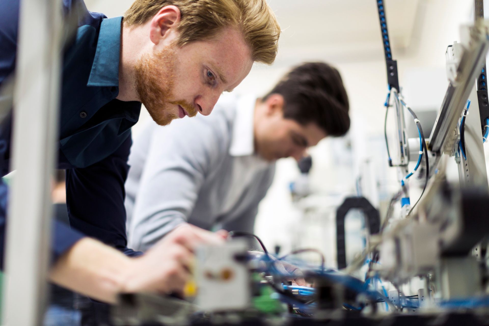 Zwei Männer arbeiten in einer Fabrik an einer Maschine.