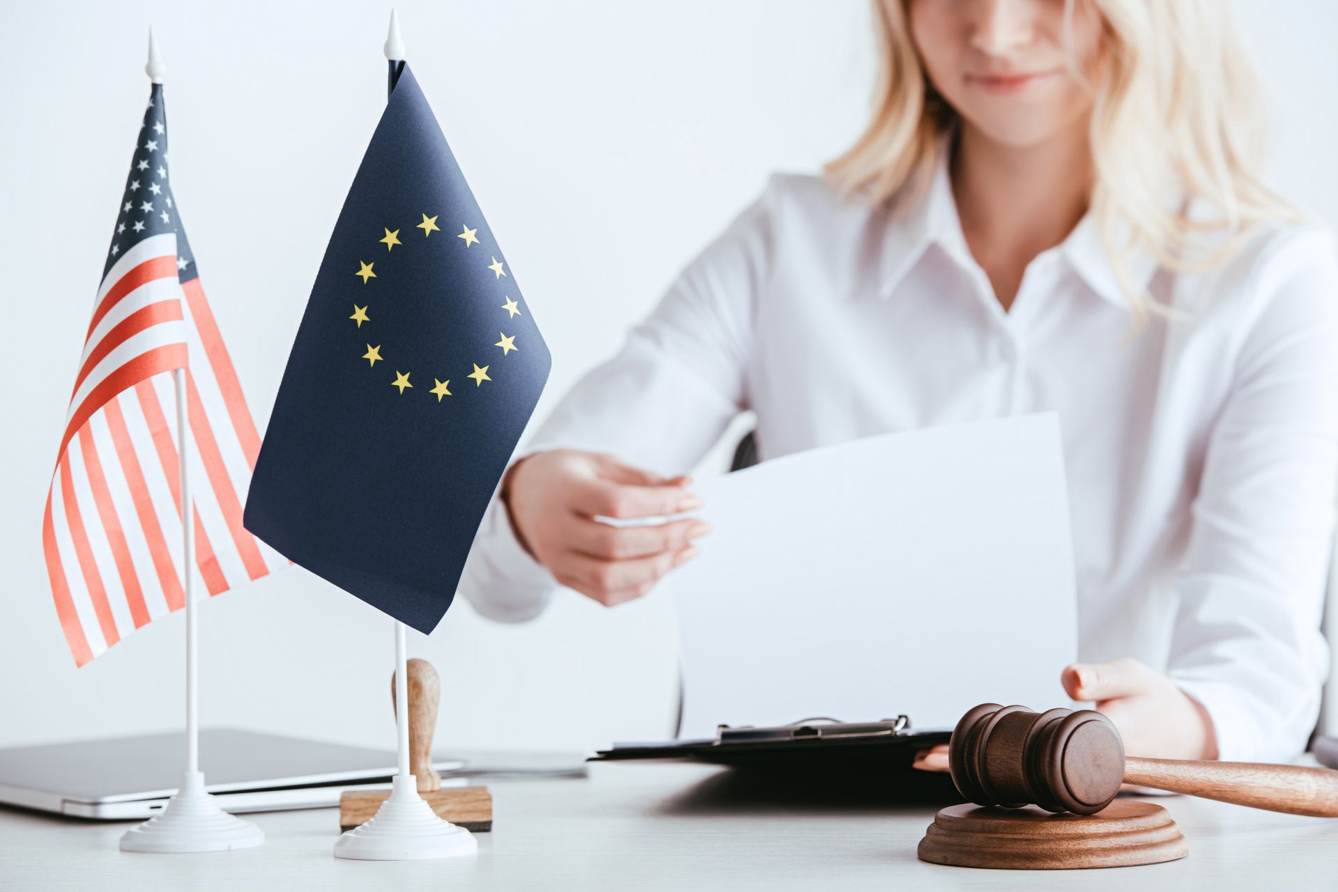 A woman is sitting at a table with a judge 's gavel and flags.