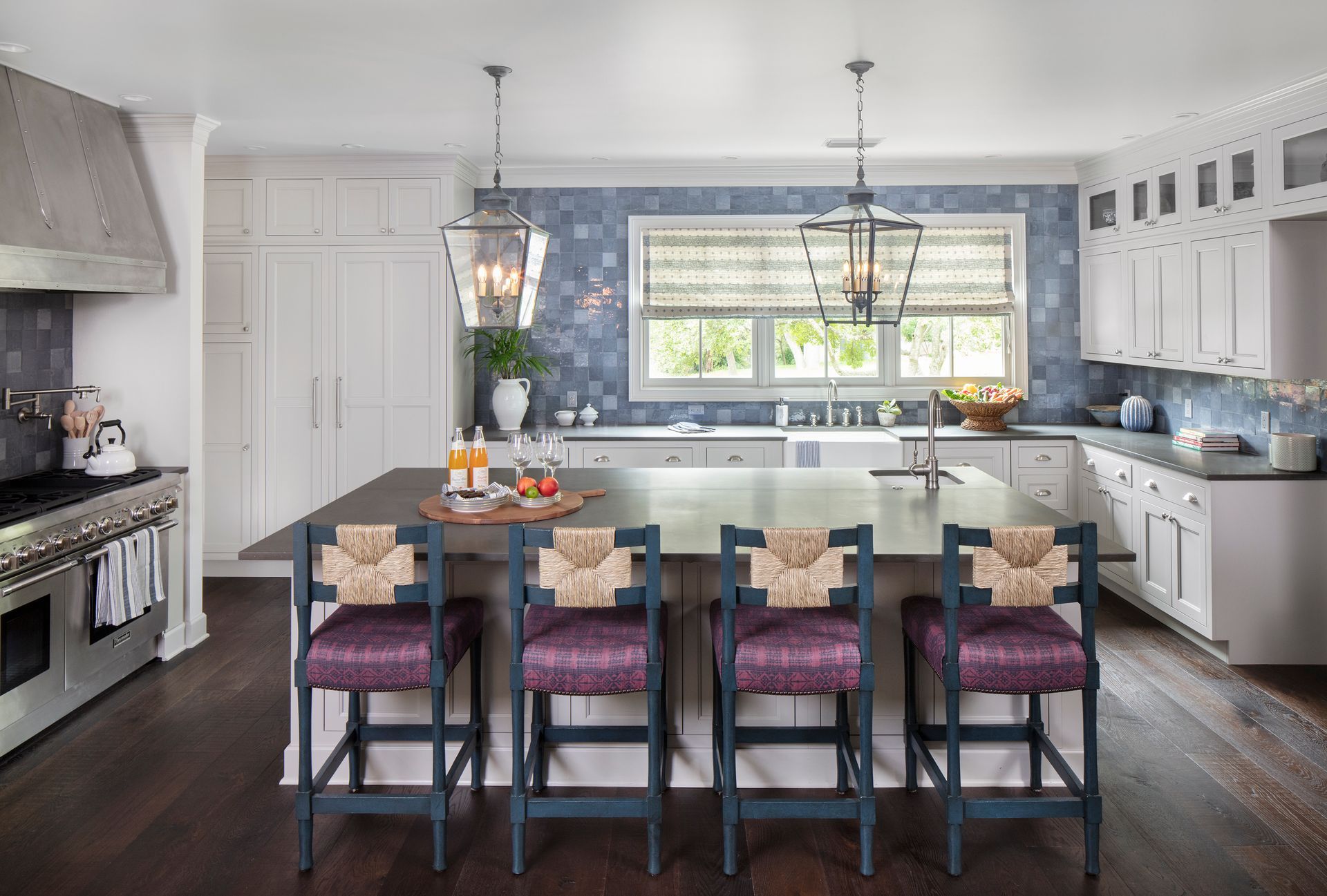 Modern galley kitchen with dark cabinets, white counters, wood floor, and stainless steel appliances