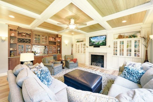 Bright living room with cream sofas, blue pillows, built-in shelves, fireplace, and wall-mounted TV
