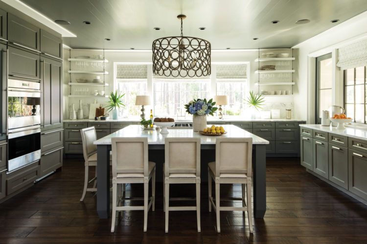 Modern kitchen with white island, dark cabinets, and large windows with natural light