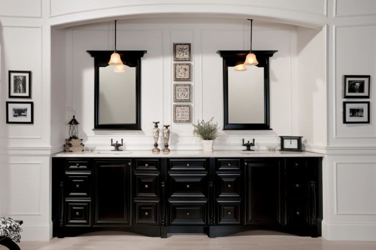 Elegant black-and-white double vanity with mirrors and wall sconces in a bathroom.