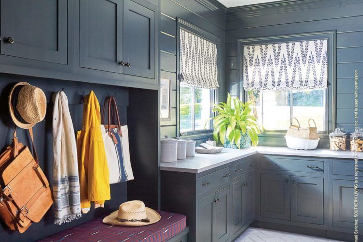 Blue mudroom with coats, hats, bench, and a bright windowed kitchen sink area
