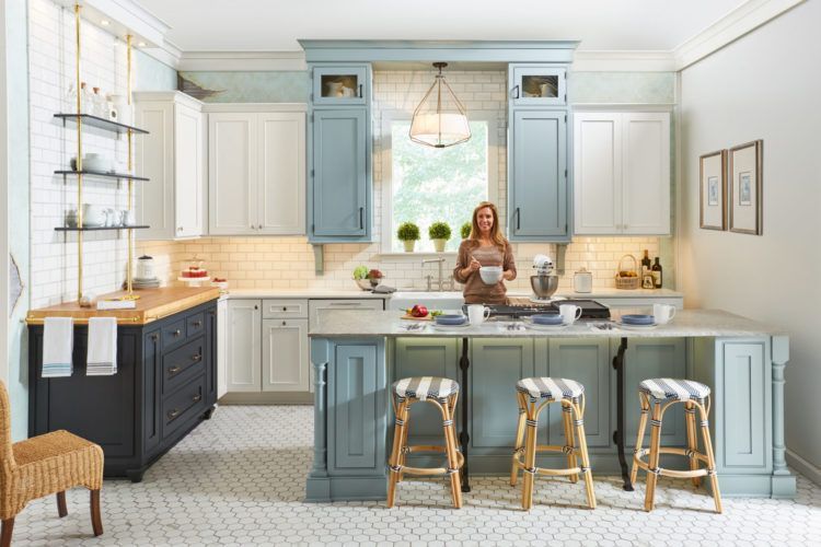 Bright kitchen with blue-gray cabinets and a woman standing behind a large island
