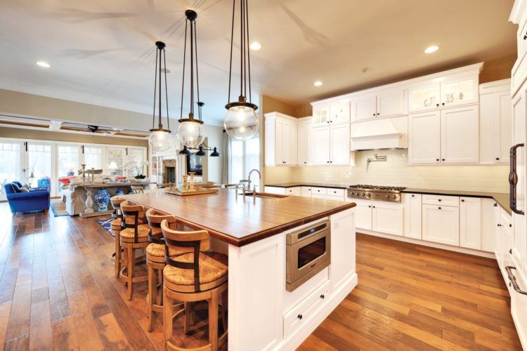 Bright modern kitchen with white cabinets, wood island, and hanging pendant lights