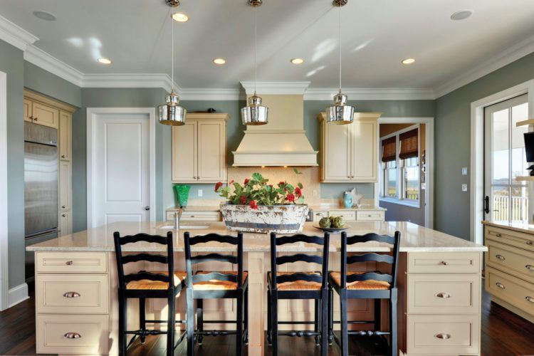Bright kitchen with a large island, six black chairs, cream cabinets, and stainless steel appliances