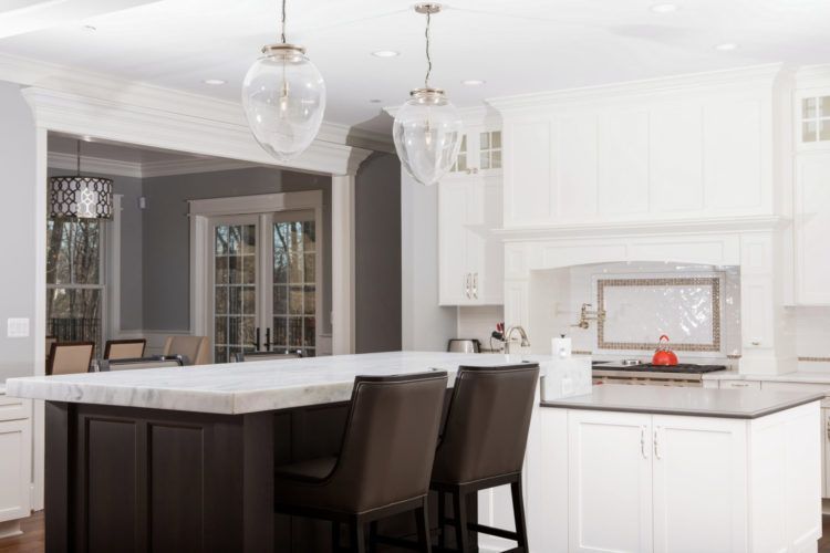 Bright white kitchen with a dark island, bar stools, and pendant lights