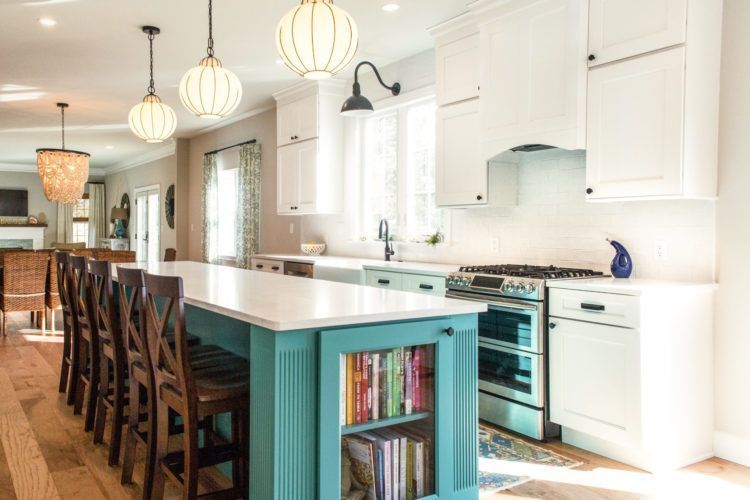 Bright white kitchen with turquoise island, bar stools, pendant lights, and hardwood floor