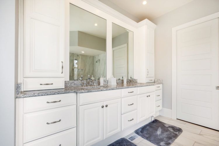 Bright white bathroom vanity with double mirrors, marble countertop, and navy rug