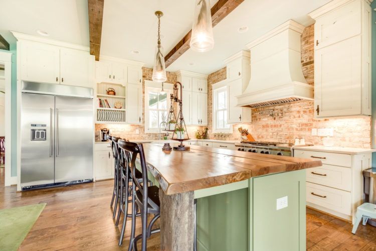 Bright modern kitchen with island, stainless fridge, white cabinets, and rustic wood accents